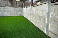 Soldier pile and precast concrete panel retaining wall with artificial turf in the foreground. Toronto, Ontario.