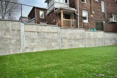 Soldier pile and precast concrete panel retaining wall with artificial turf in the foreground. Toronto, Ontario.