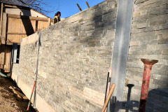 Adding a natural stone veneer to a soldier pile and concrete panel retaining wall. Burlington, Ontario.