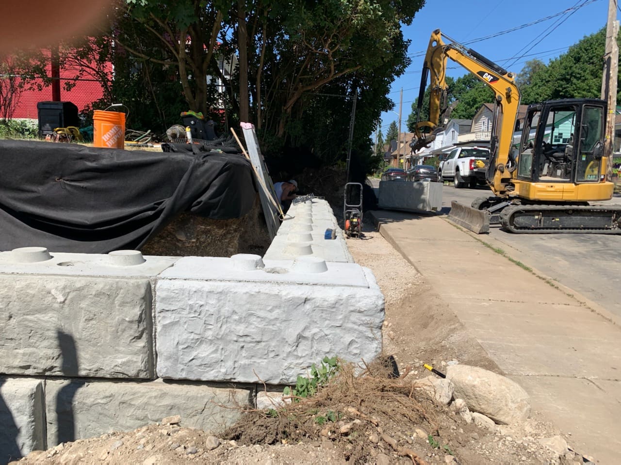 Excavator beside new concrete retaining wall