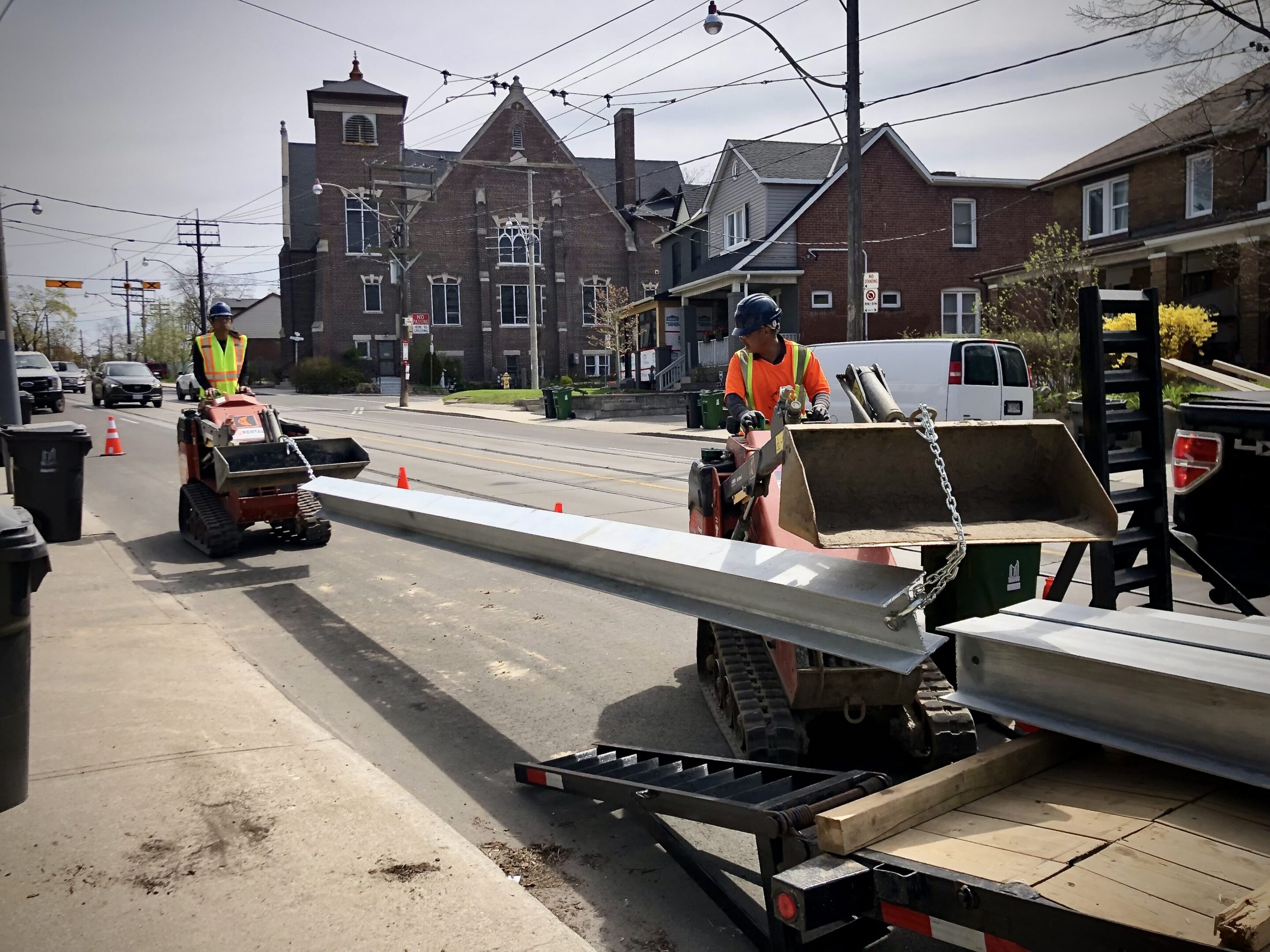 Construction workers moving metal beam on street