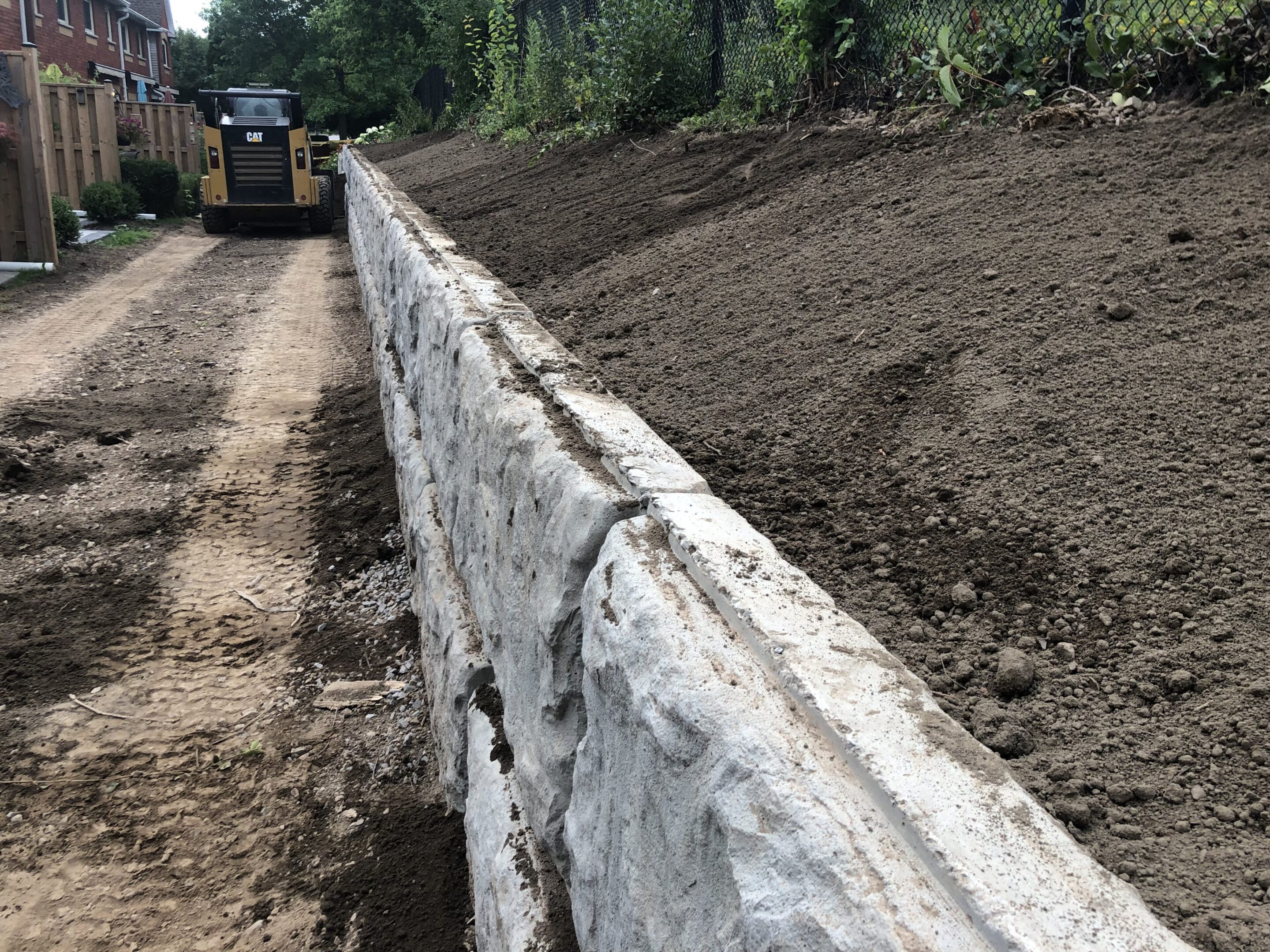 Retaining wall under construction along dirt slope