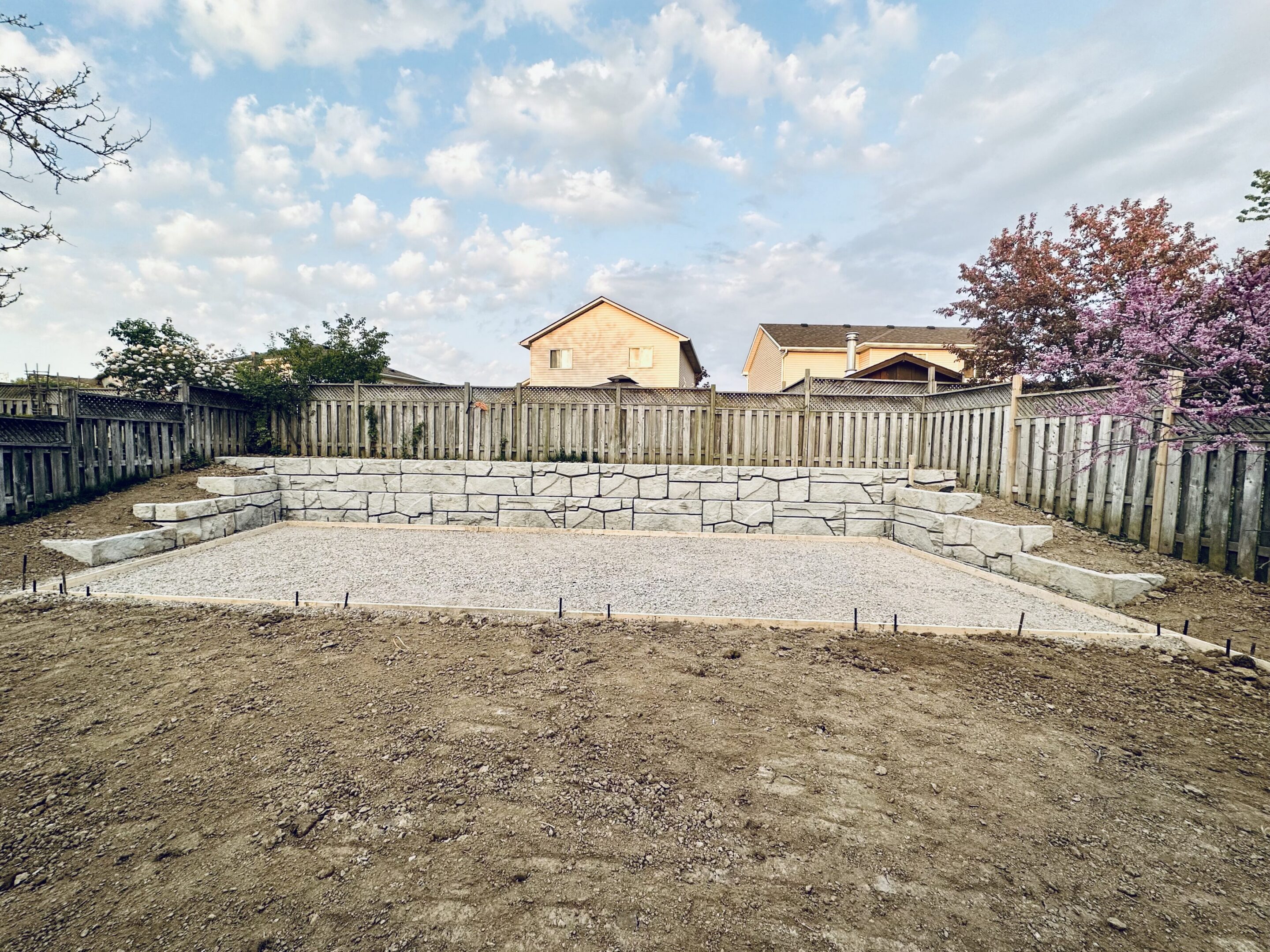 Backyard with stone retaining wall and gravel