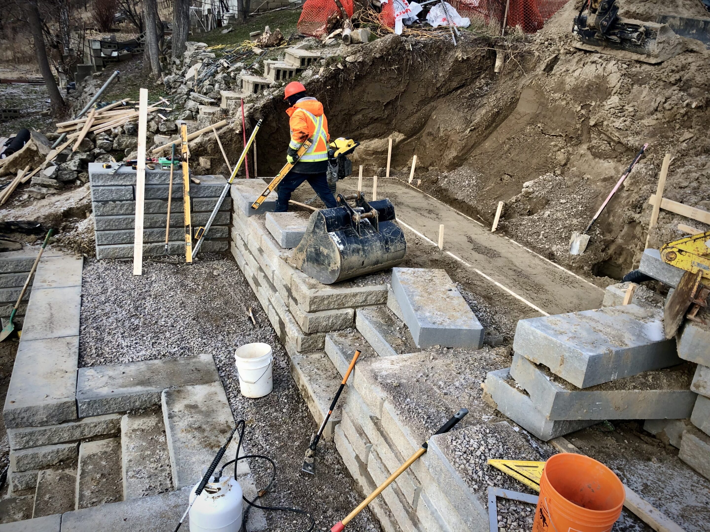 Construction worker compacting gravel on retaining wall