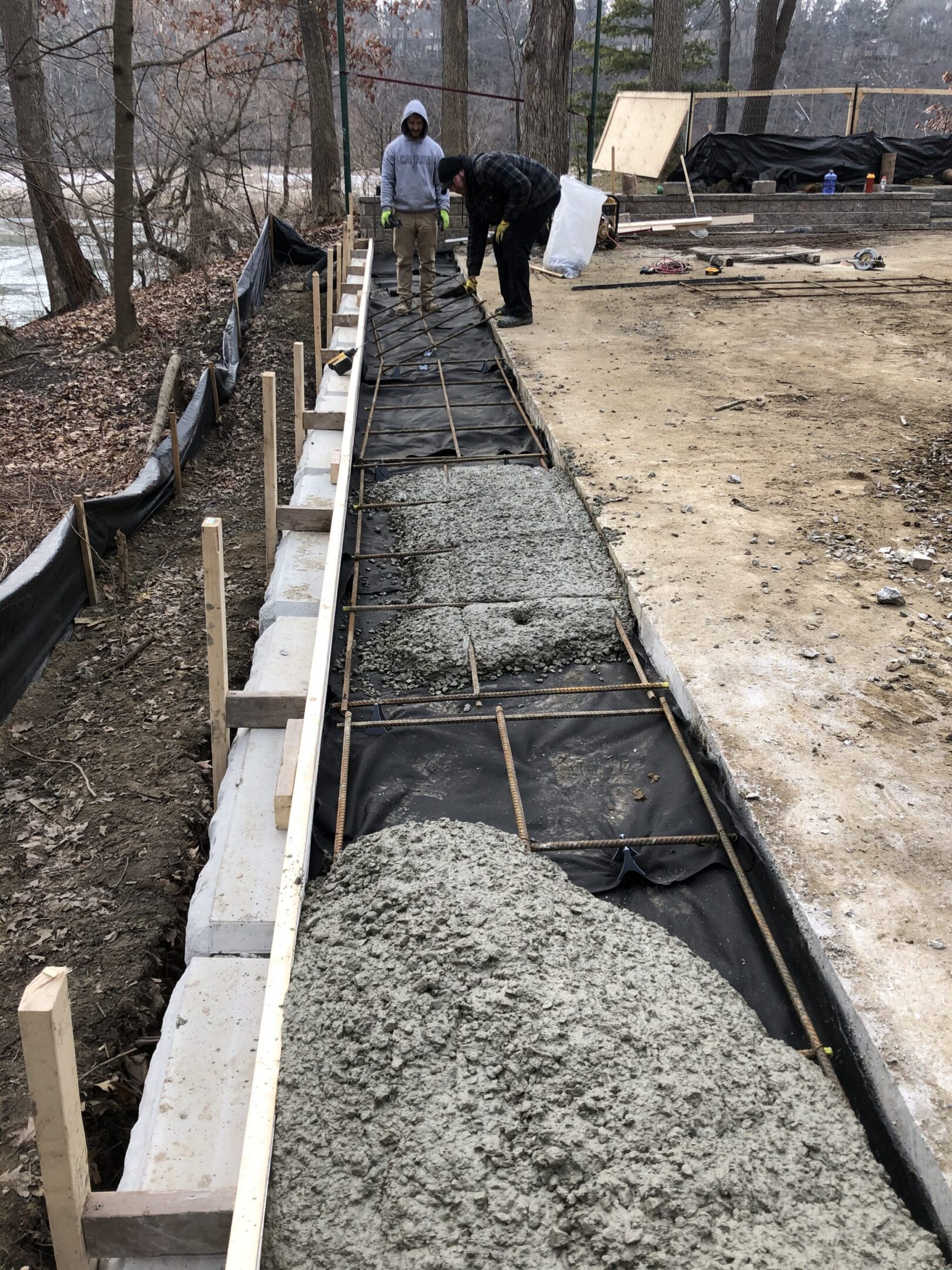 Workers pouring concrete along foundation forms