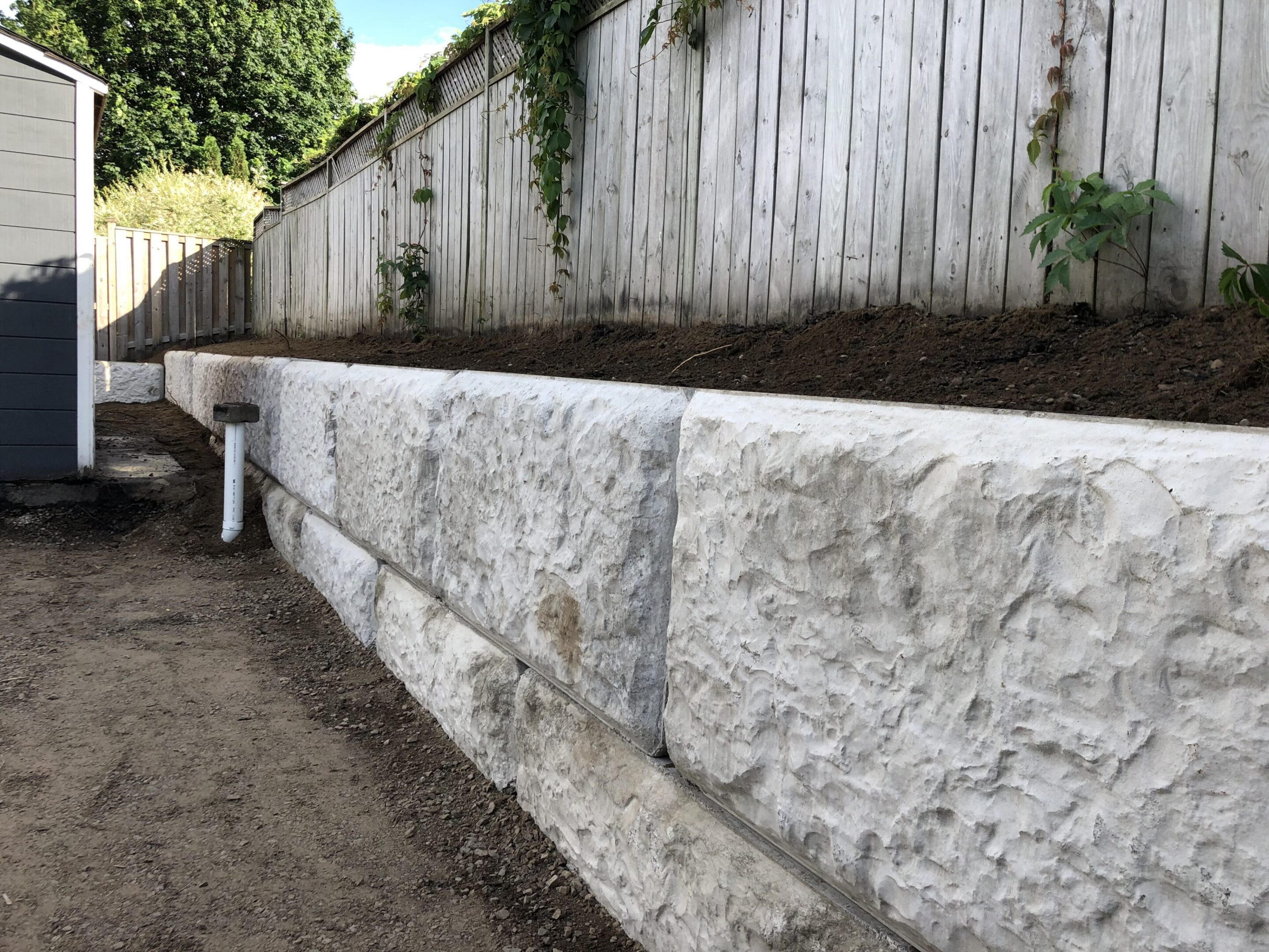 White textured retaining wall along backyard fence