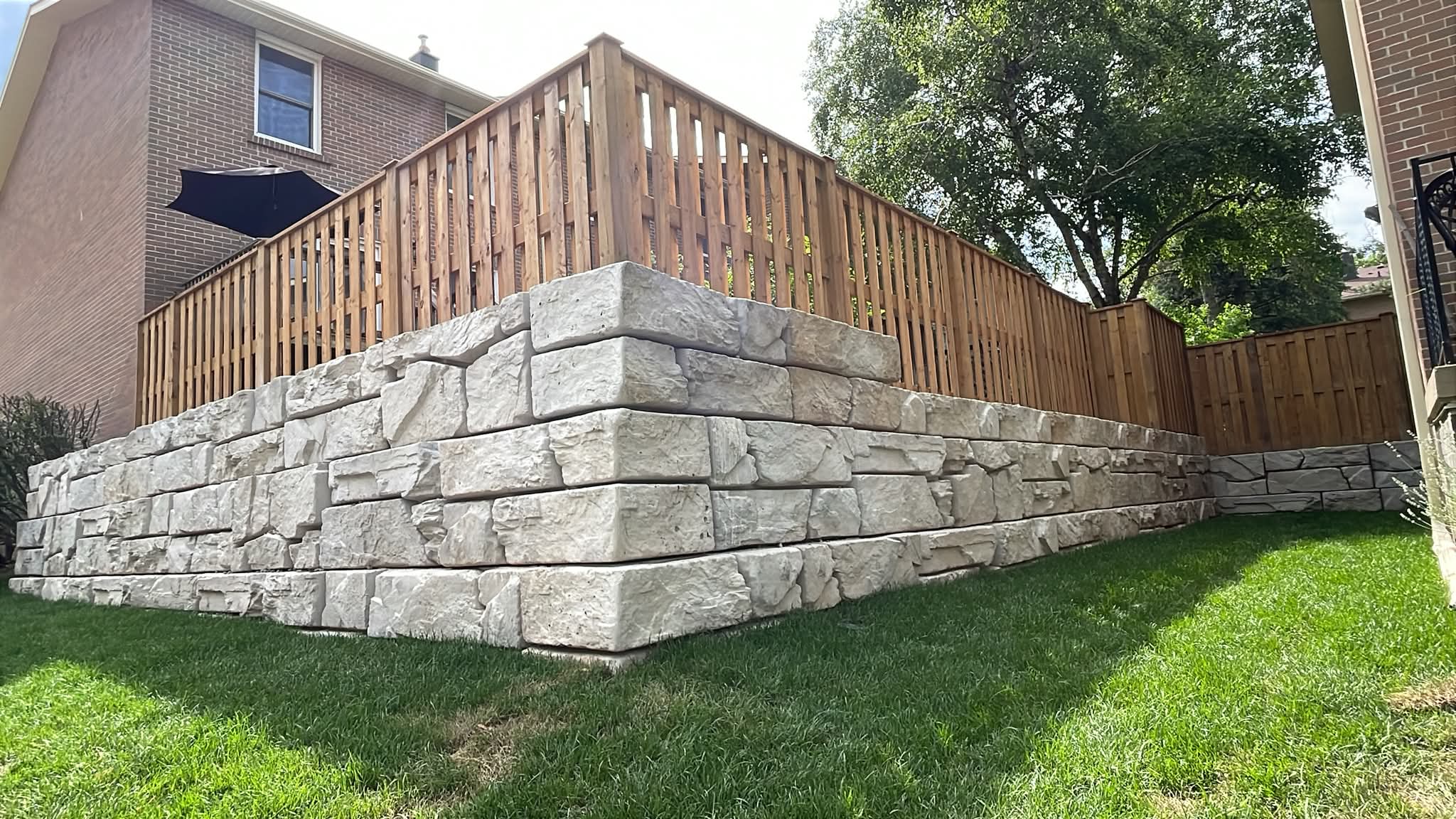 Residential stone retaining wall with wooden fence