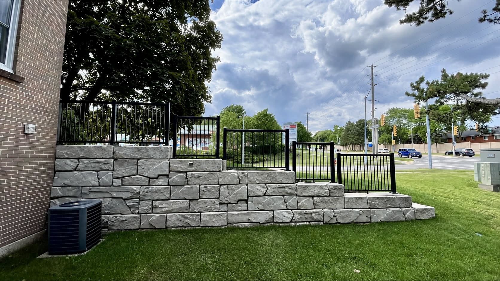 Stone retaining wall with black metal fence