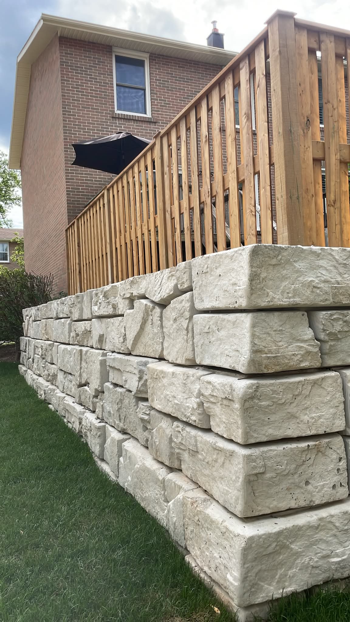 Limestone retaining wall with wooden deck railing