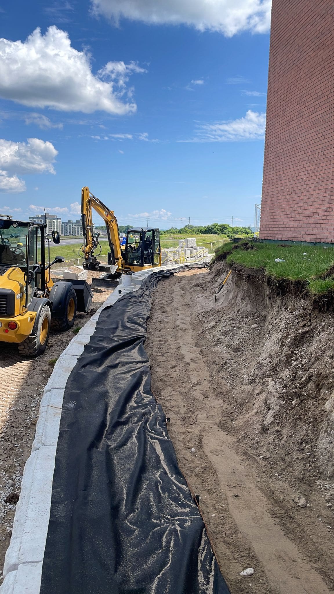 Construction excavation trench with excavators beside building